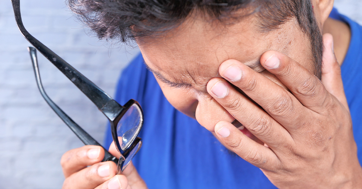 A man covering an eye in pain