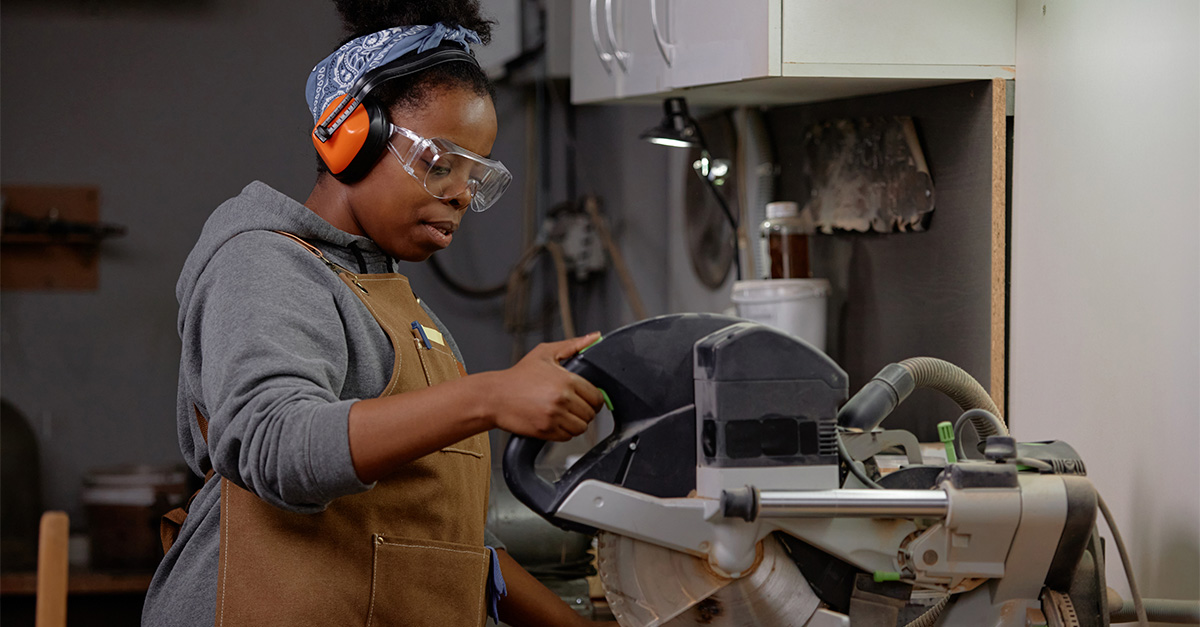 A lady wearing safety goggles while operating a circular saw.